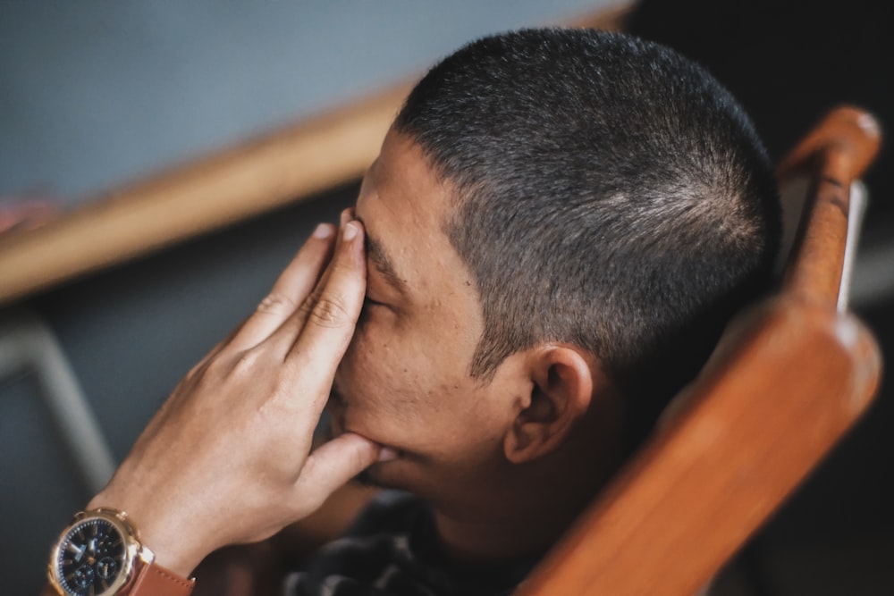 man in black shirt covering his face