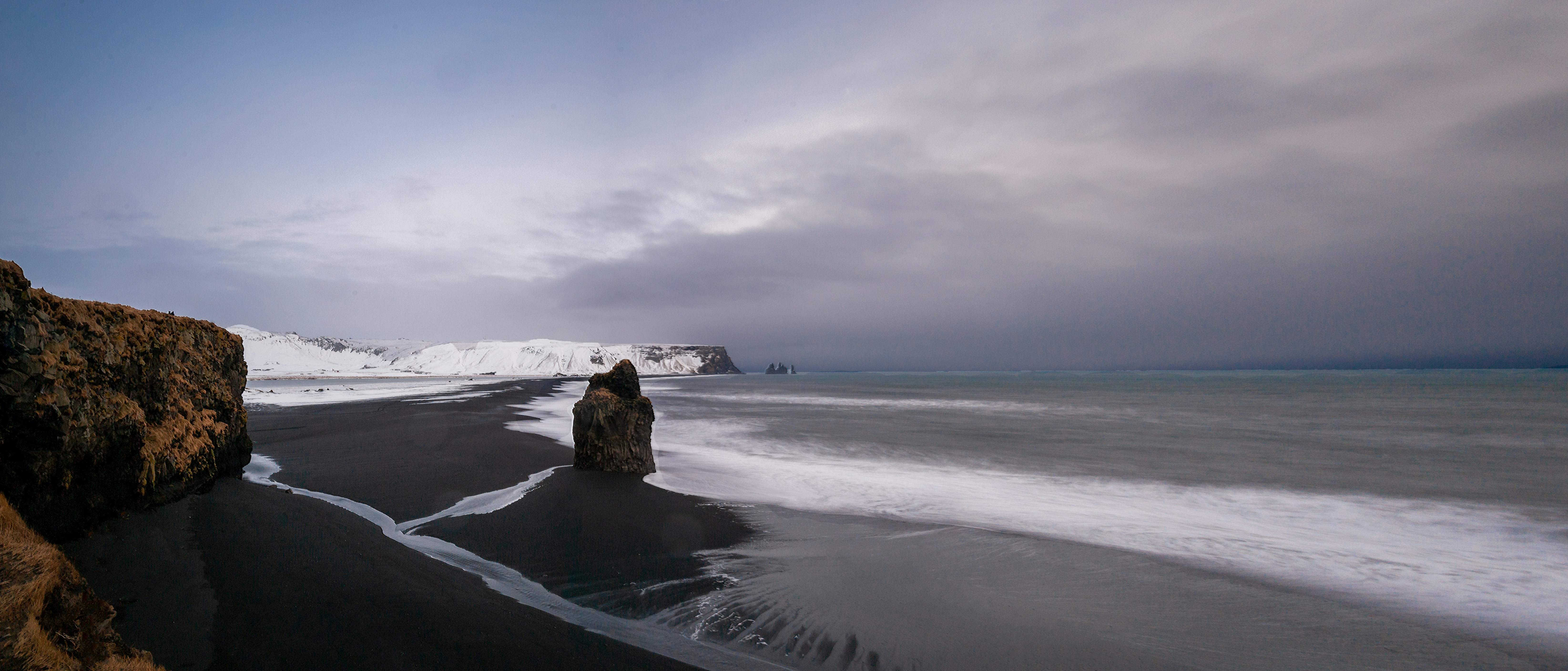 Black sand beach with dramatic waves and volcanic rock formations in Iceland