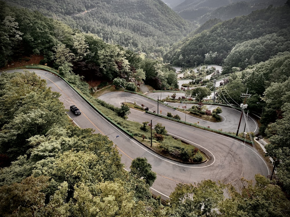 cars on road near green trees and mountains during daytime