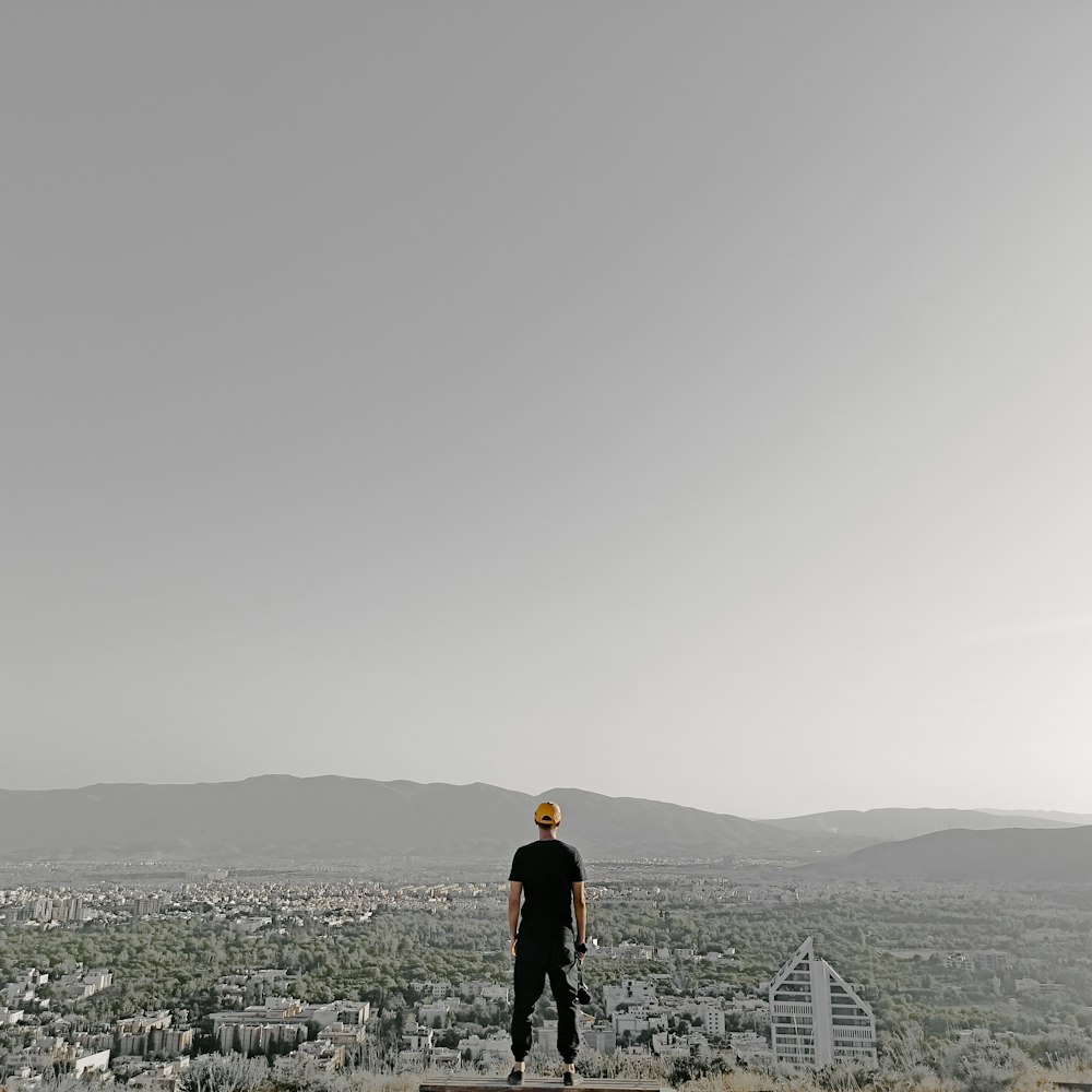 uomo in giacca nera in piedi sulla cima della montagna durante il giorno