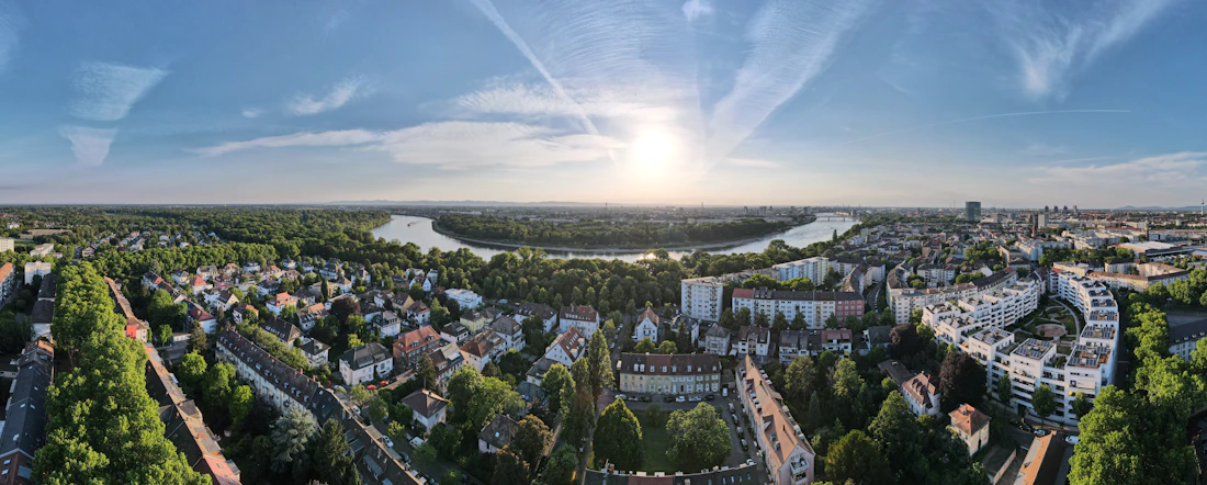 Luftpanorama von Mannheim mit Rheinbogen und Morgensonne über grünen Stadtvierteln