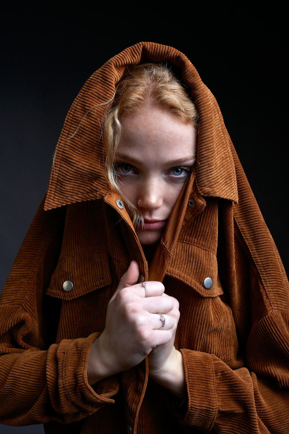 woman in brown coat holding her hair