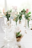 Close-up of delicate glassware and floral centerpiece on a rustic wooden table.