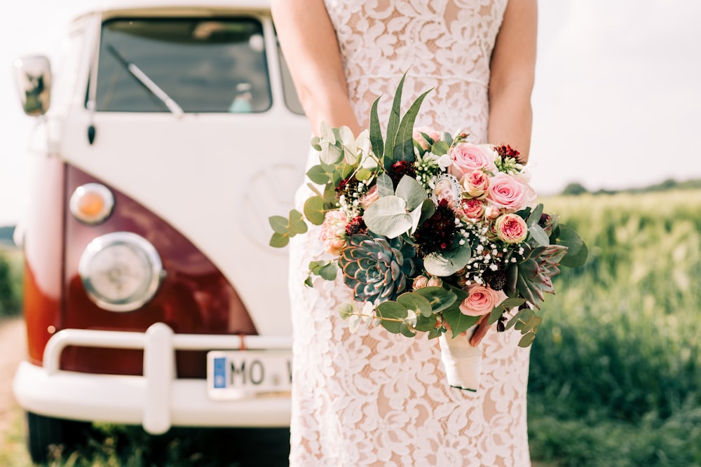 woman in white floral dress holding bouquet of flowers