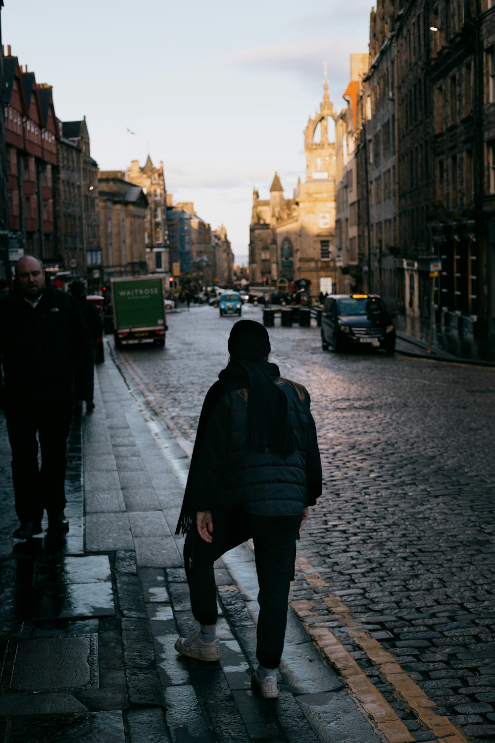 man in black jacket walking on sidewalk during daytime