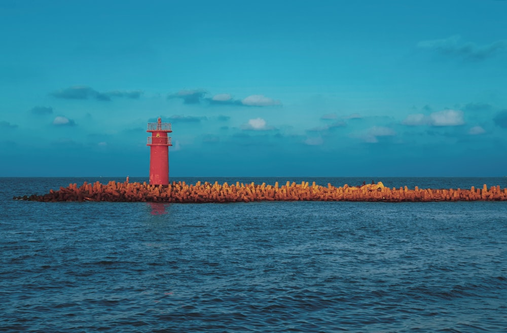 white and brown lighthouse on body of water under blue sky during daytime