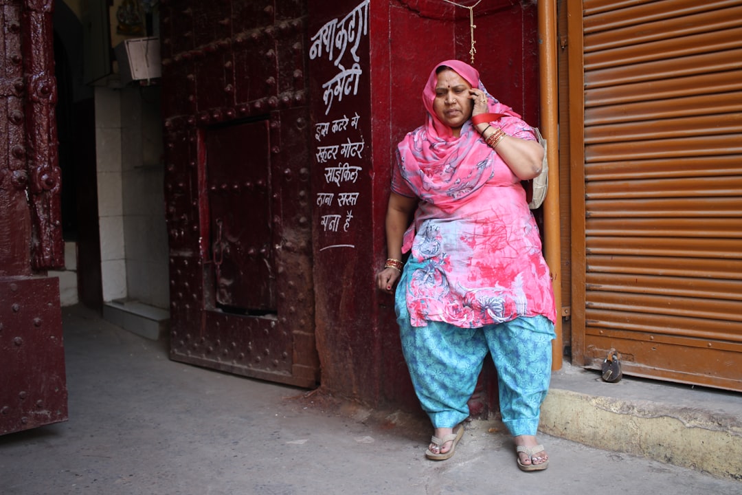 woman in pink hijab standing beside red and black wooden door