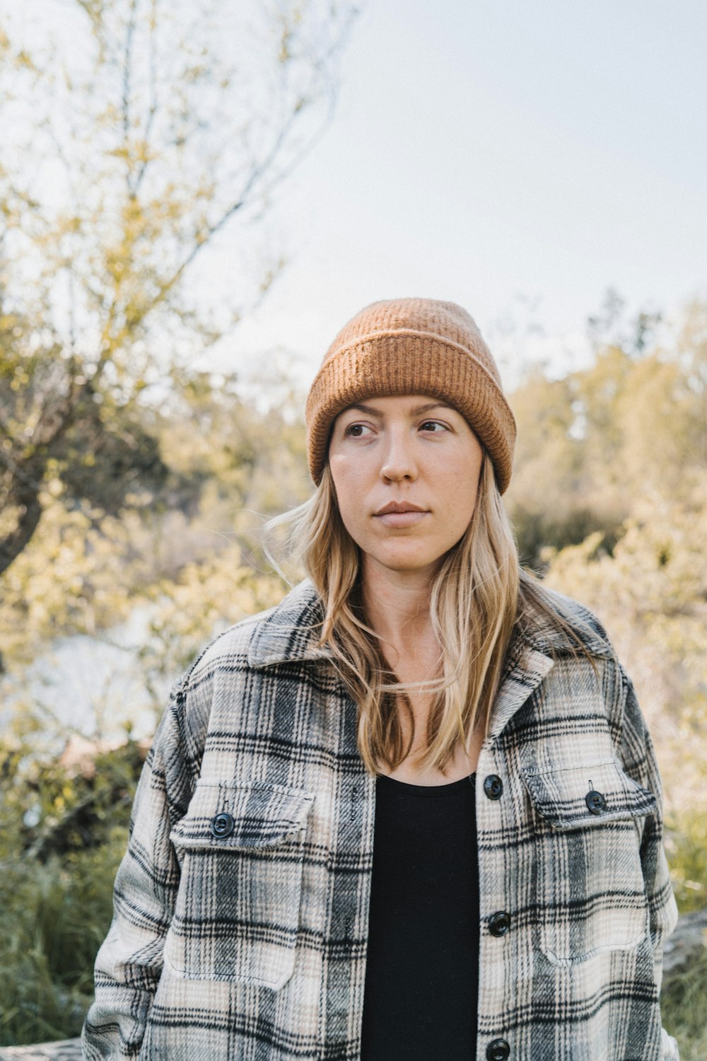 woman in brown knit cap and black and white plaid jacket