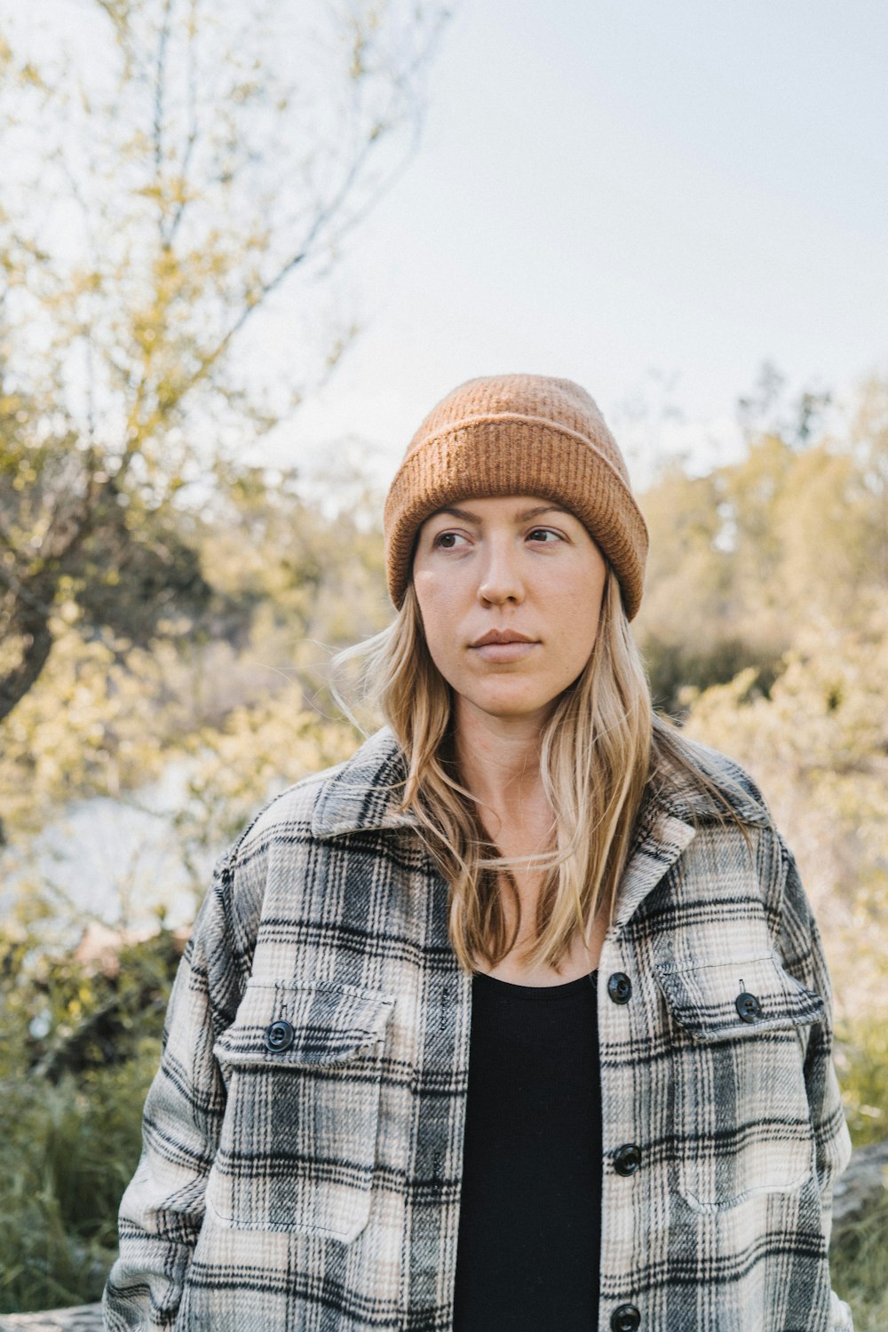 Mujer con gorra de punto marrón y chaqueta a cuadros blanco y negro