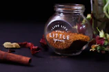 a glass jar filled with spices next to a flower