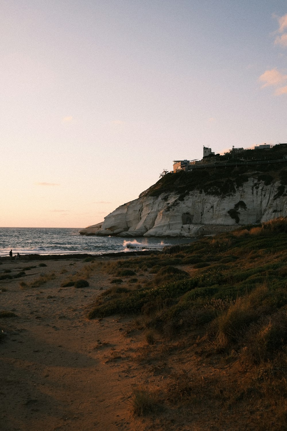 white concrete building on brown rock formation near sea during daytime