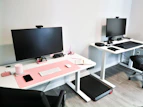 A technician configuring a modern office setup with multiple monitors, keyboards, and peripherals.