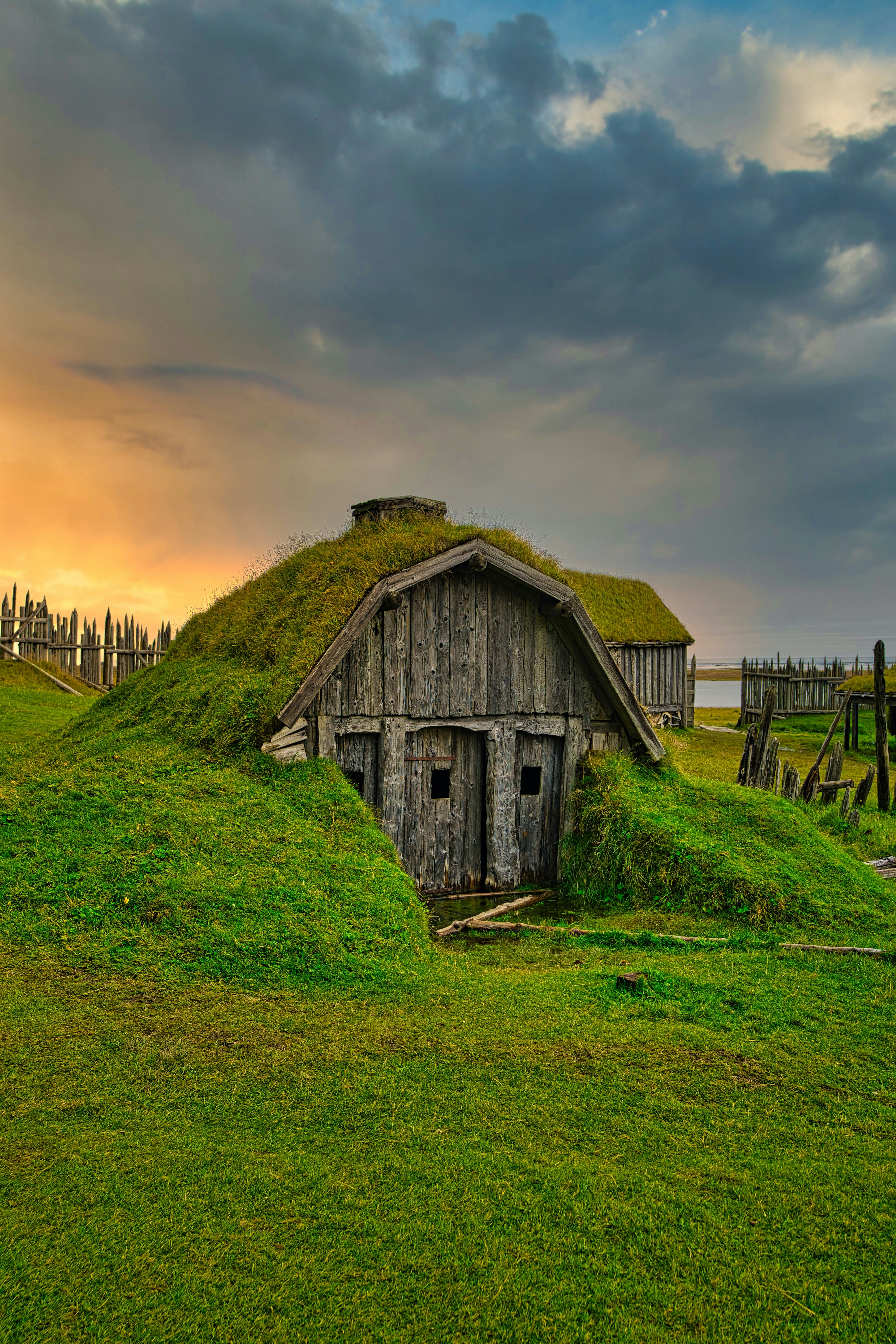 brown wooden house on green grass field during sunset
