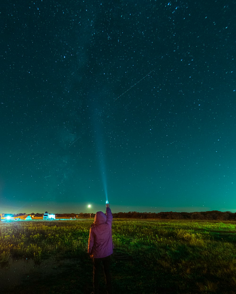 woman in purple jacket standing on green grass field during night time