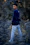 man in blue hoodie and white pants standing on rocky ground