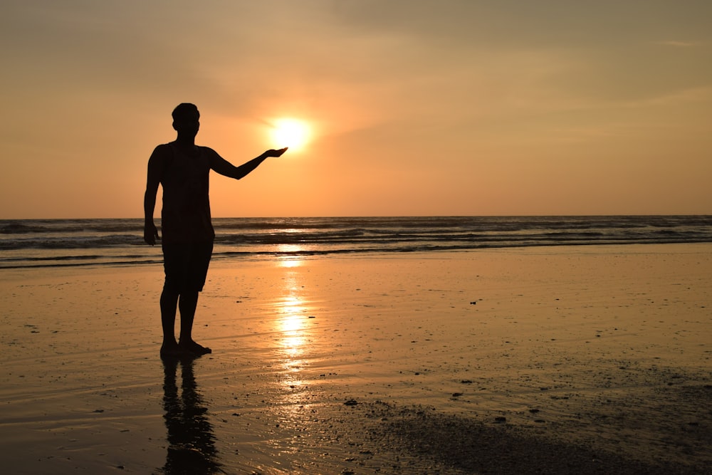 a man standing on top of a beach next to the ocean