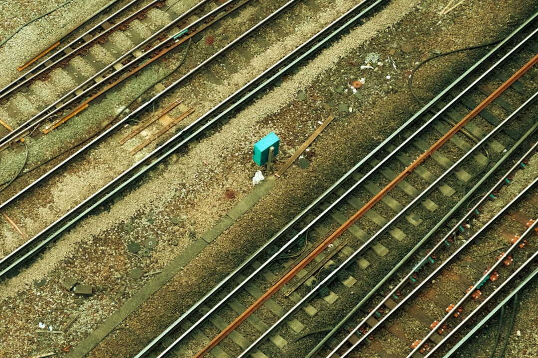 person in blue jacket standing on train rail