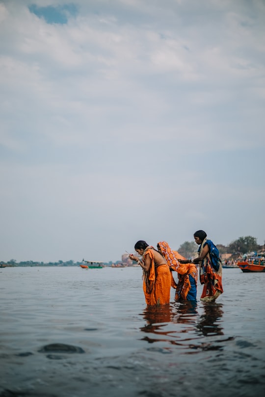 people in orange and blue shirts on body of water during daytime in Vrindavan India