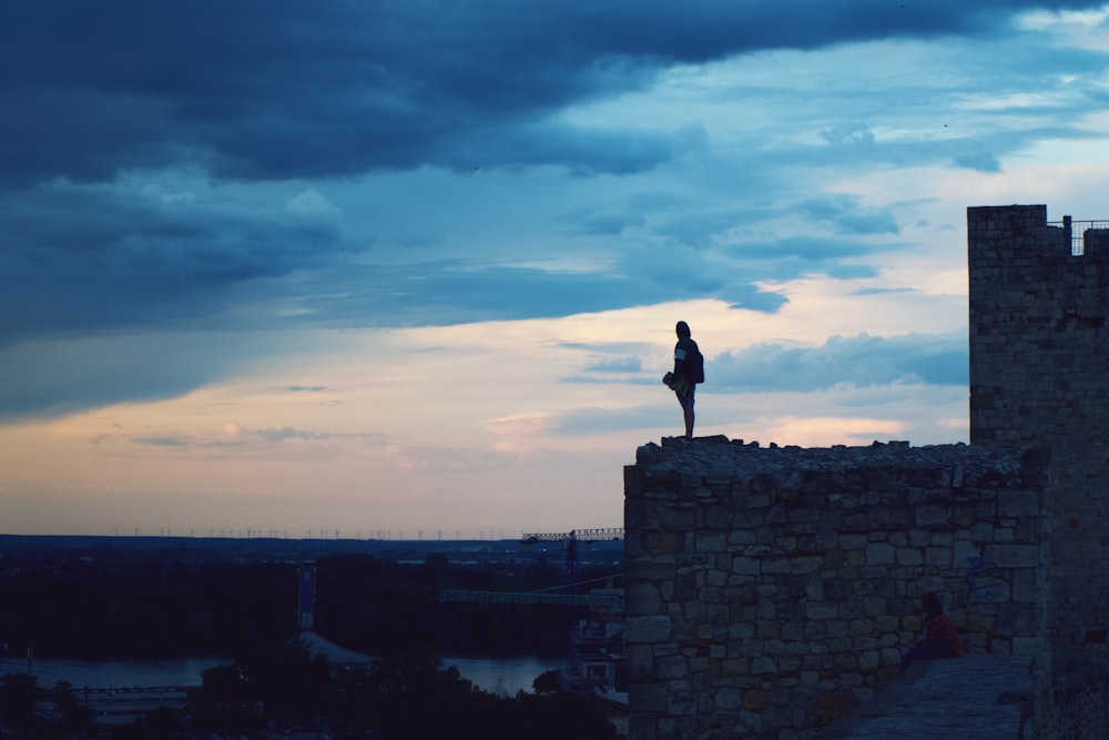 silhouette dell'uomo in piedi sulla cima dell'edificio durante il tramonto