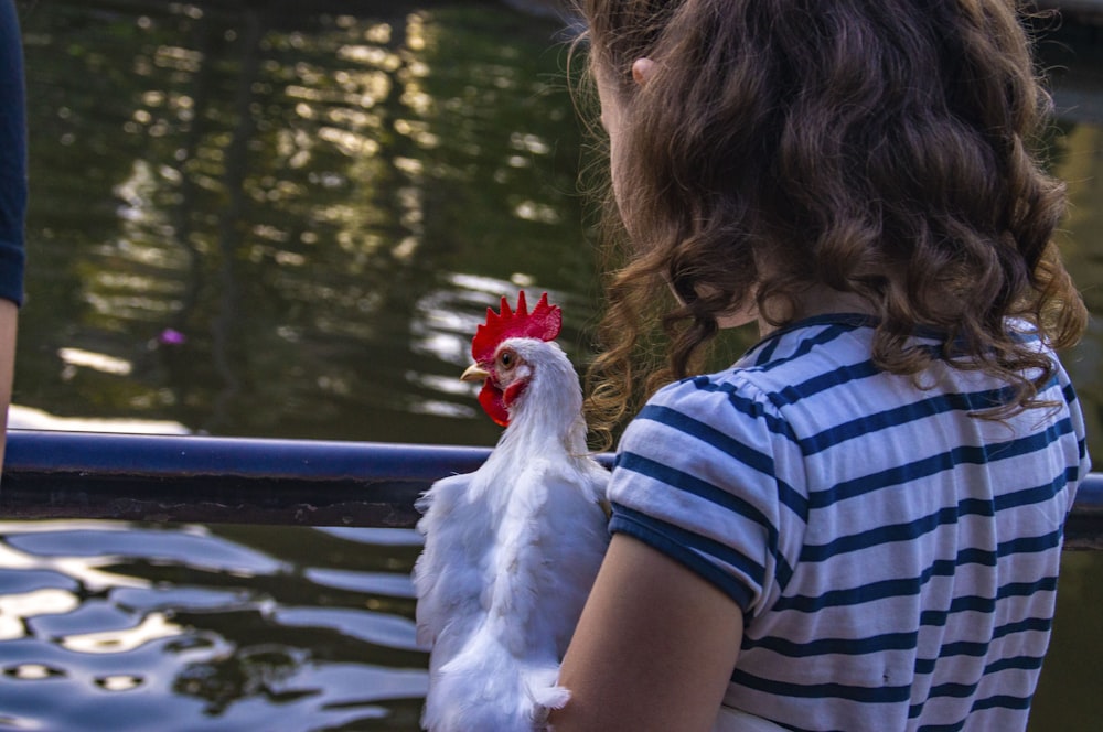 girl in blue and white stripe shirt holding white chicken