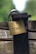 A close-up of a brass padlock with the brand name 'ABUS' and numbers '55/40' engraved on it. The lock is attached to an old, rusted metal latch on a wooden surface. The background is blurred, showing shades of green, suggesting a natural outdoor setting.