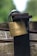 A close-up of a brass padlock with the brand name 'ABUS' and numbers '55/40' engraved on it. The lock is attached to an old, rusted metal latch on a wooden surface. The background is blurred, showing shades of green, suggesting a natural outdoor setting.