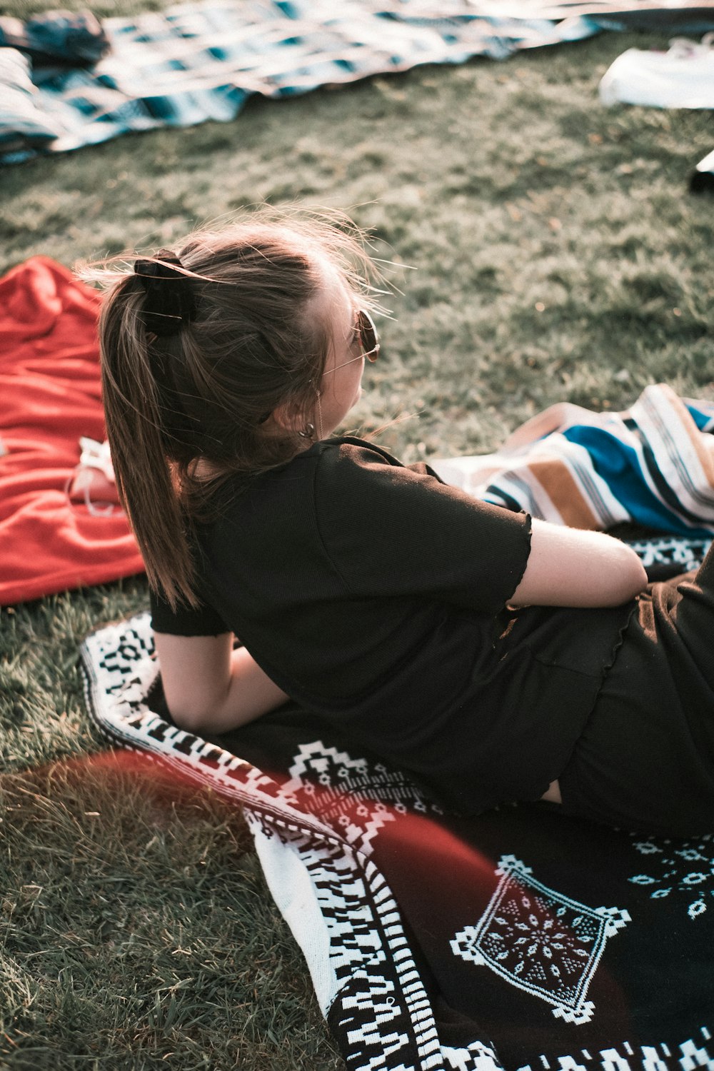 woman in black shirt lying on green grass during daytime