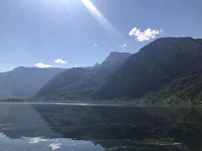 A serene mountain lake reflecting the clear blue sky at sunrise.