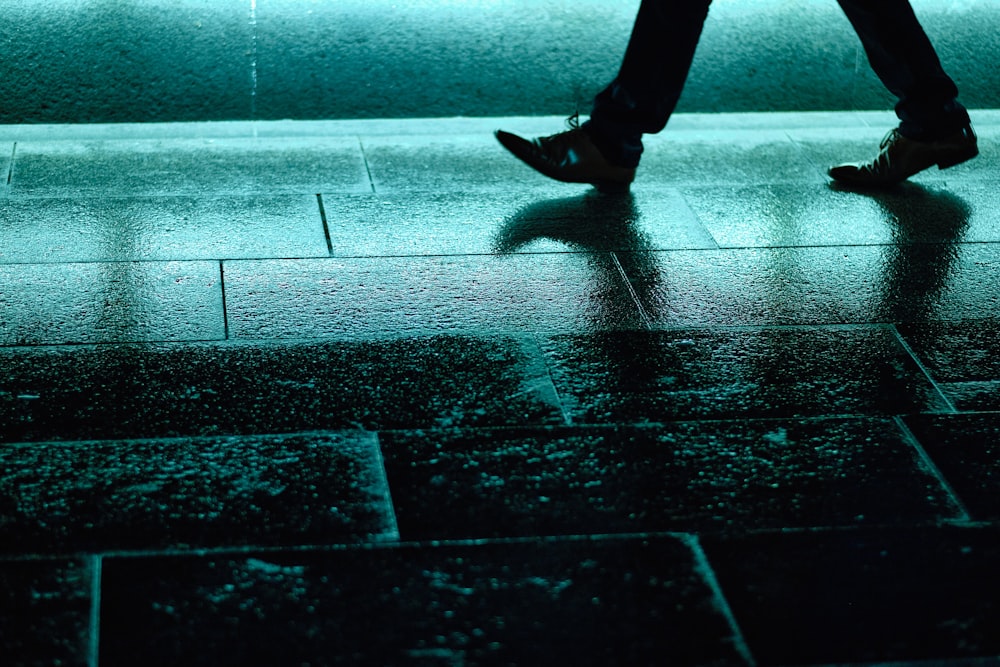 person in black pants and black shoes walking on sidewalk