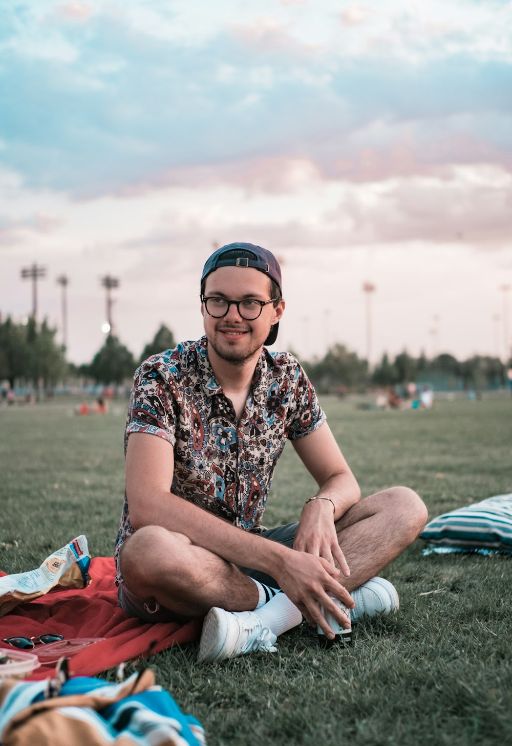 낮 동안 푸른 잔디밭에 앉아 흑백 꽃무늬 버튼 업 셔츠를 입은 남자