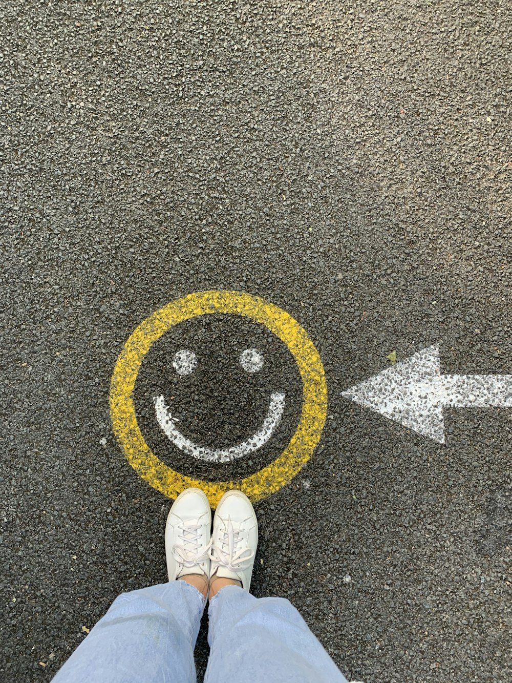 person in white shoes standing on gray concrete road