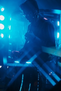 A solo guitarist performing on stage with colorful lights.