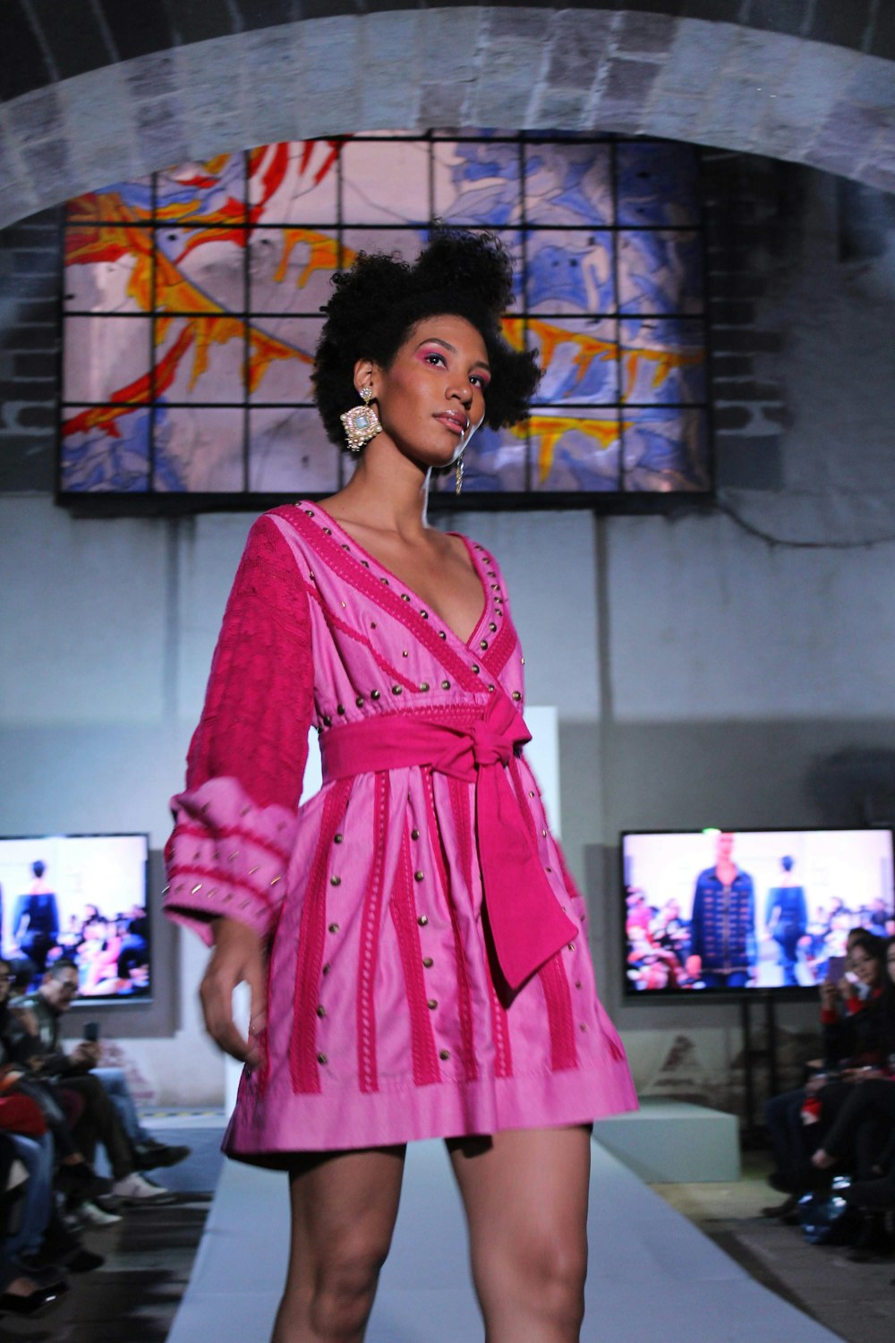 woman in pink and white polka dot dress standing near store