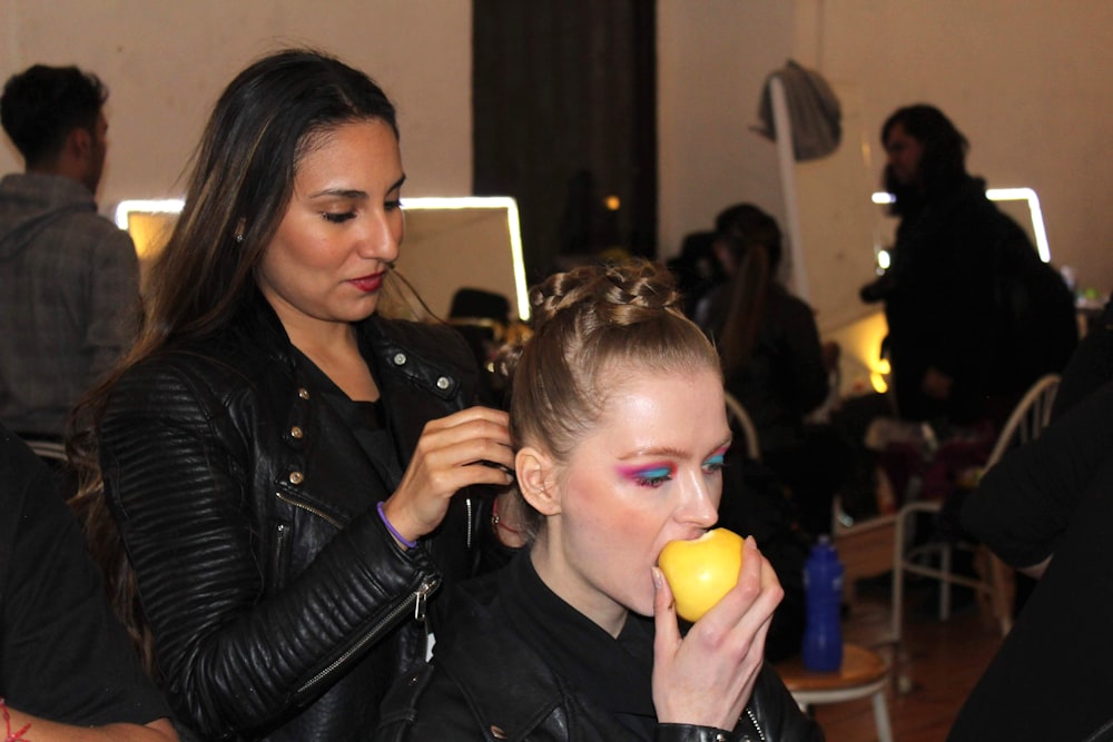 woman in black leather jacket holding yellow plastic cup