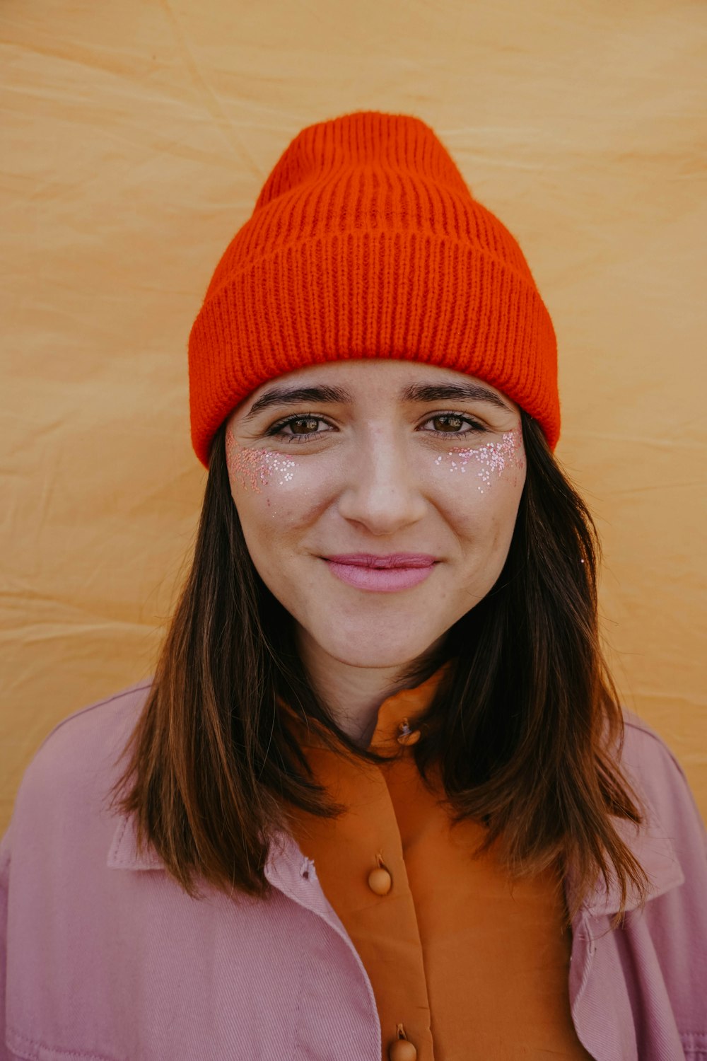オレンジ色のニット帽をかぶった女性が微笑む