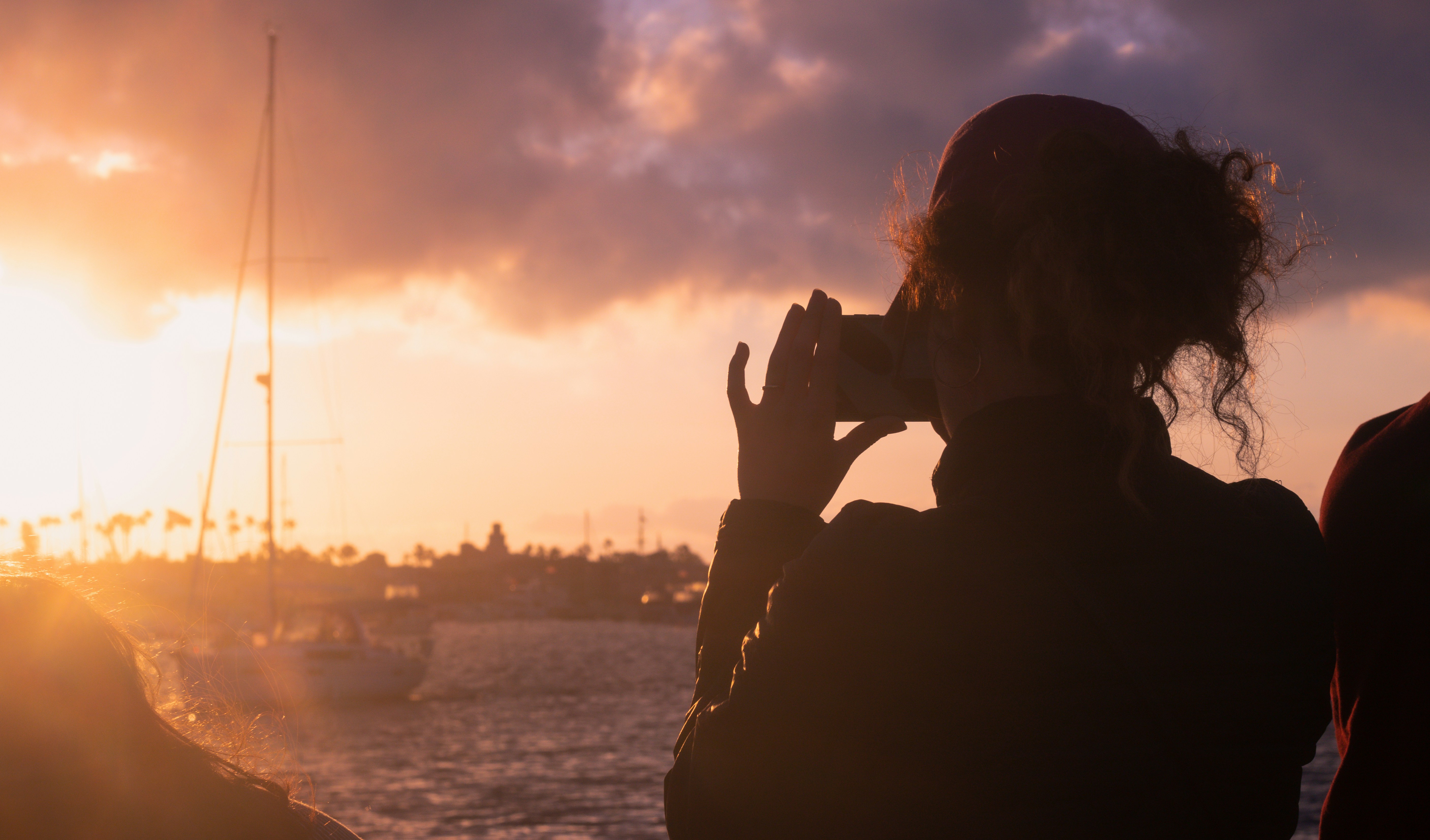 silhouette of person covering face with hands during sunset