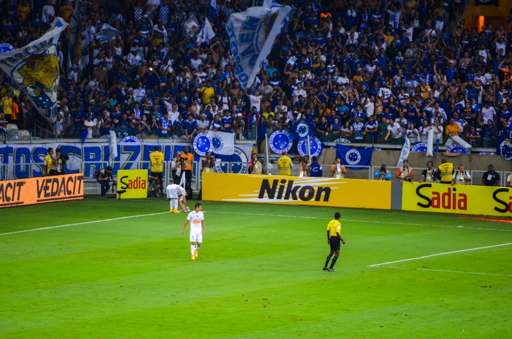 man in white soccer jersey shirt and black pants standing on green field