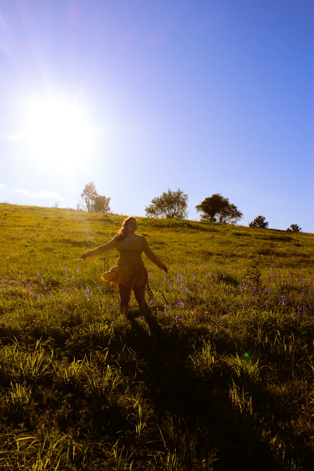 woman in brown dress walking on green grass field during daytime