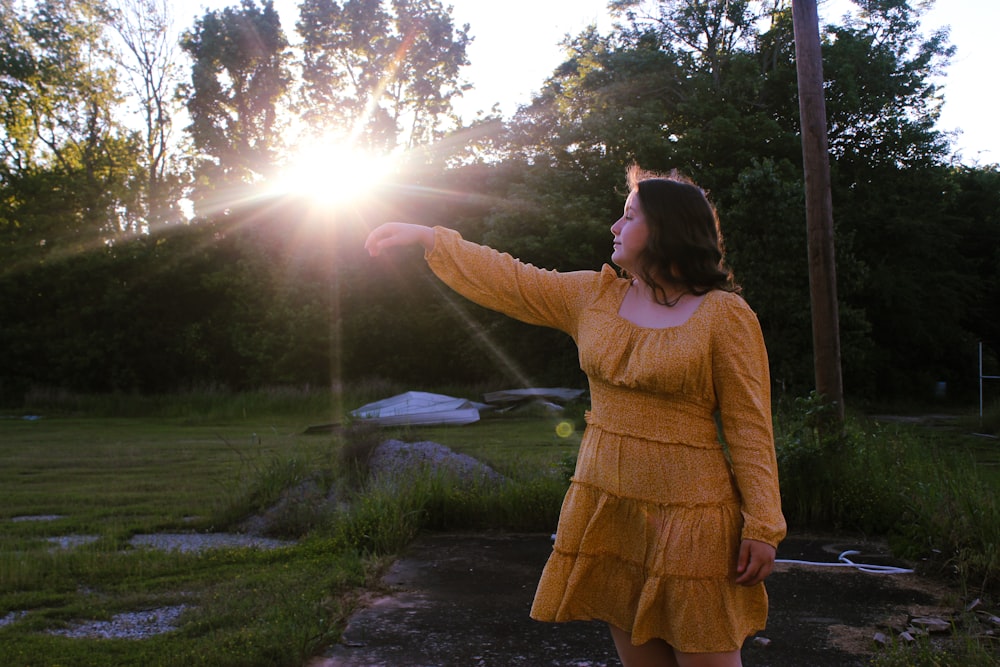 woman in yellow long sleeve dress standing on road during daytime