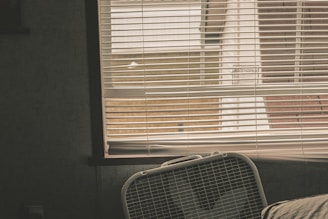 A sleek stand fan in a bright living room with sunlight streaming through the window.