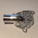 A metallic, intricately machined component with a tubular protrusion and detailed geometric patterns on its surface, likely a part for mechanical or industrial use.