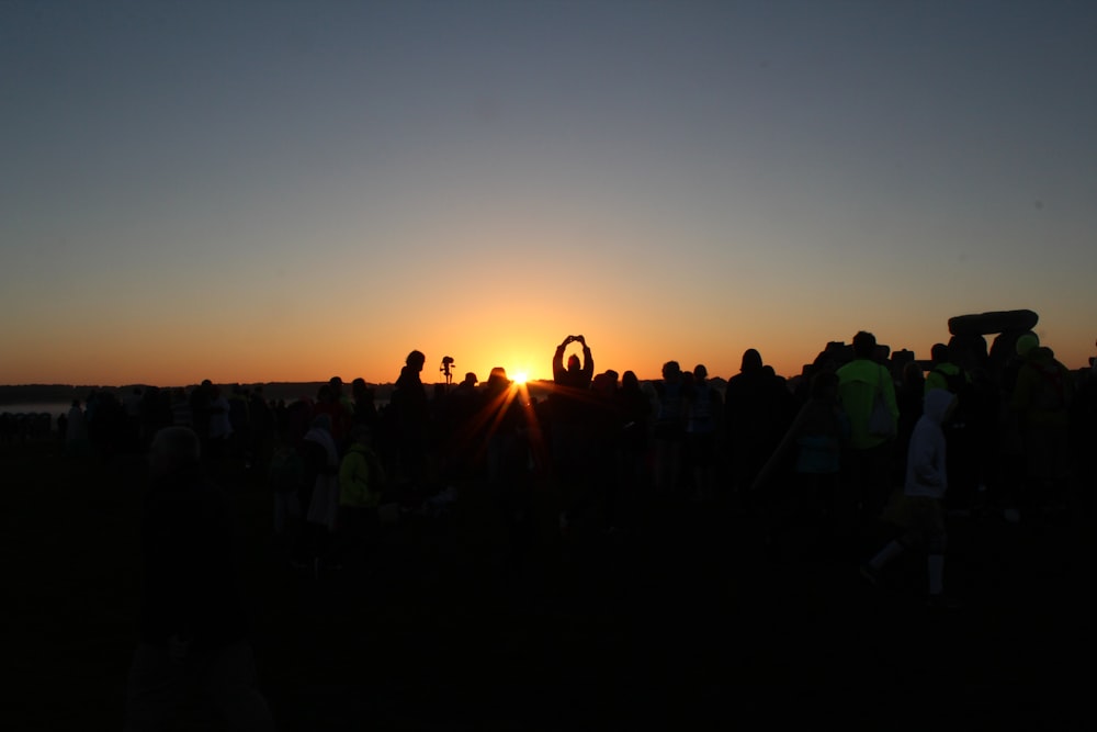 Gente de pie en el campo durante la puesta del sol