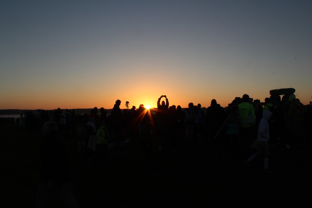 people standing on field during sunset