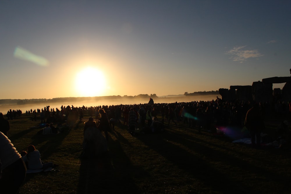 people standing on field during sunset