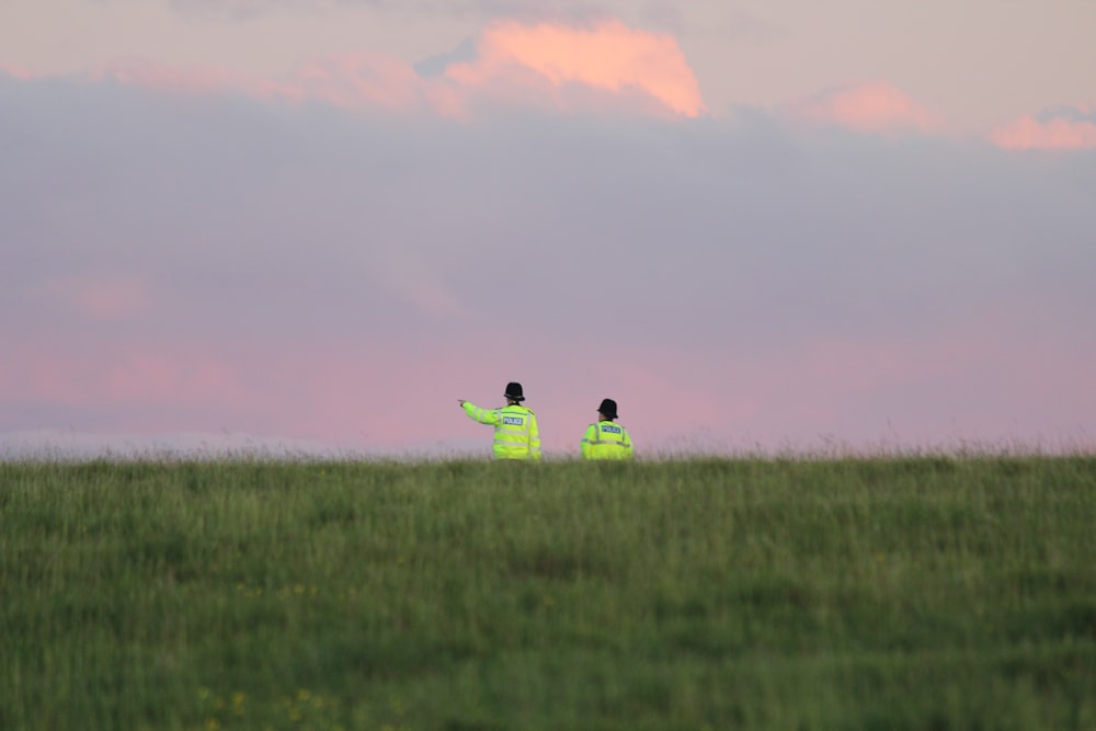 2 person sitting on green grass field during sunset