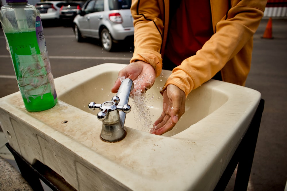 person in orange jacket washing hand
