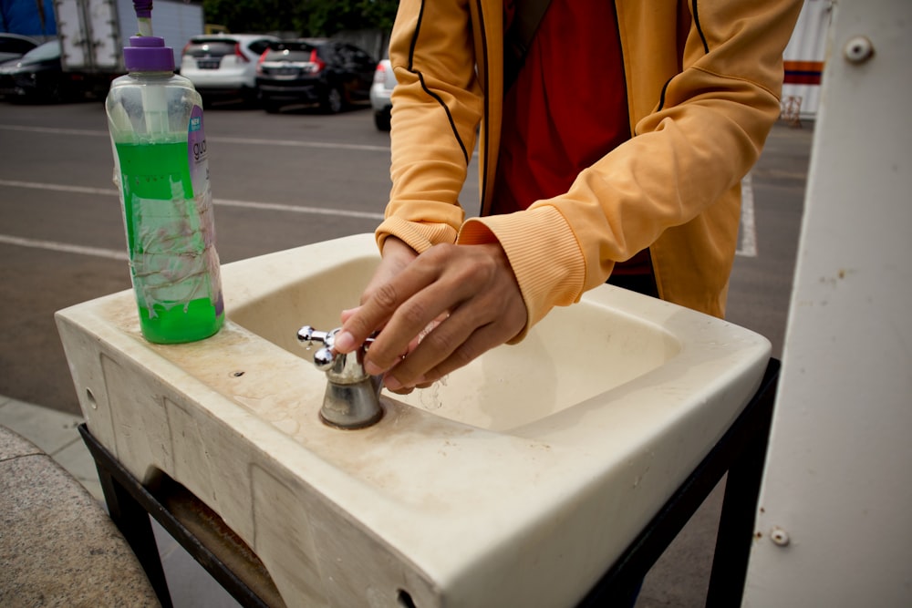 woman in yellow jacket holding silver faucet