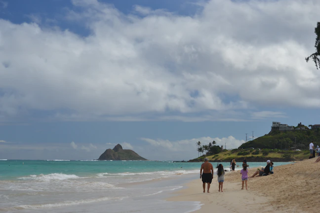 A family enjoying a private beach daypass with clear turquoise waters and palm trees in the background.