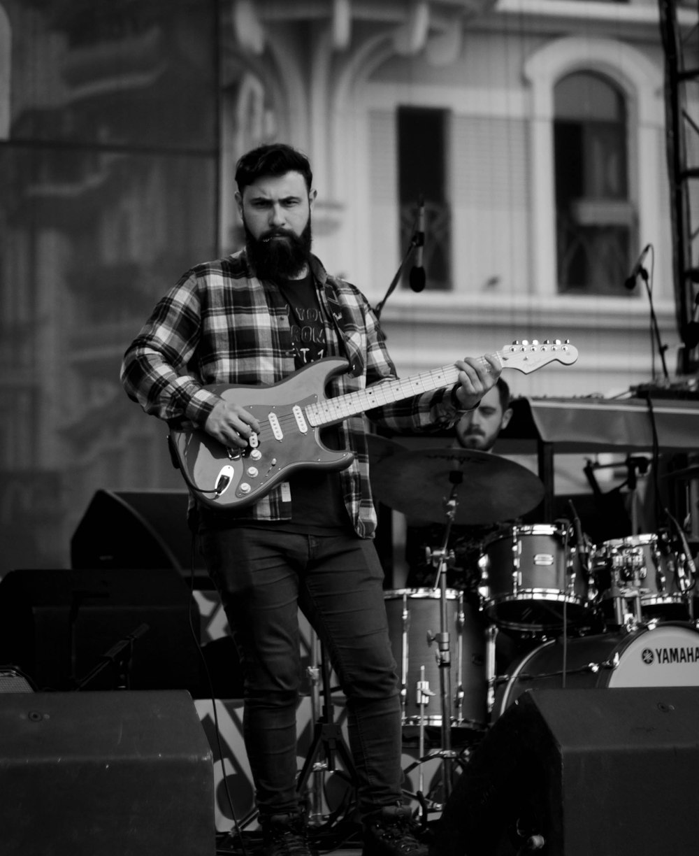 man playing electric guitar in grayscale photography