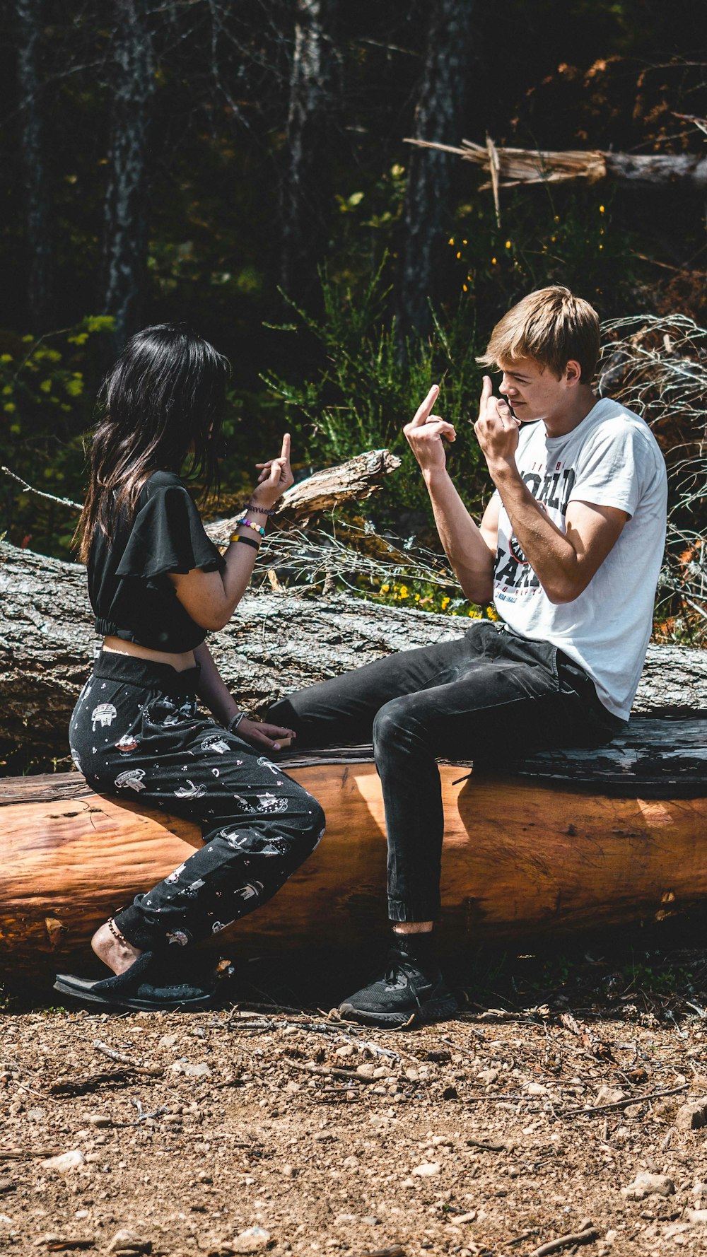 man and woman sitting on brown log